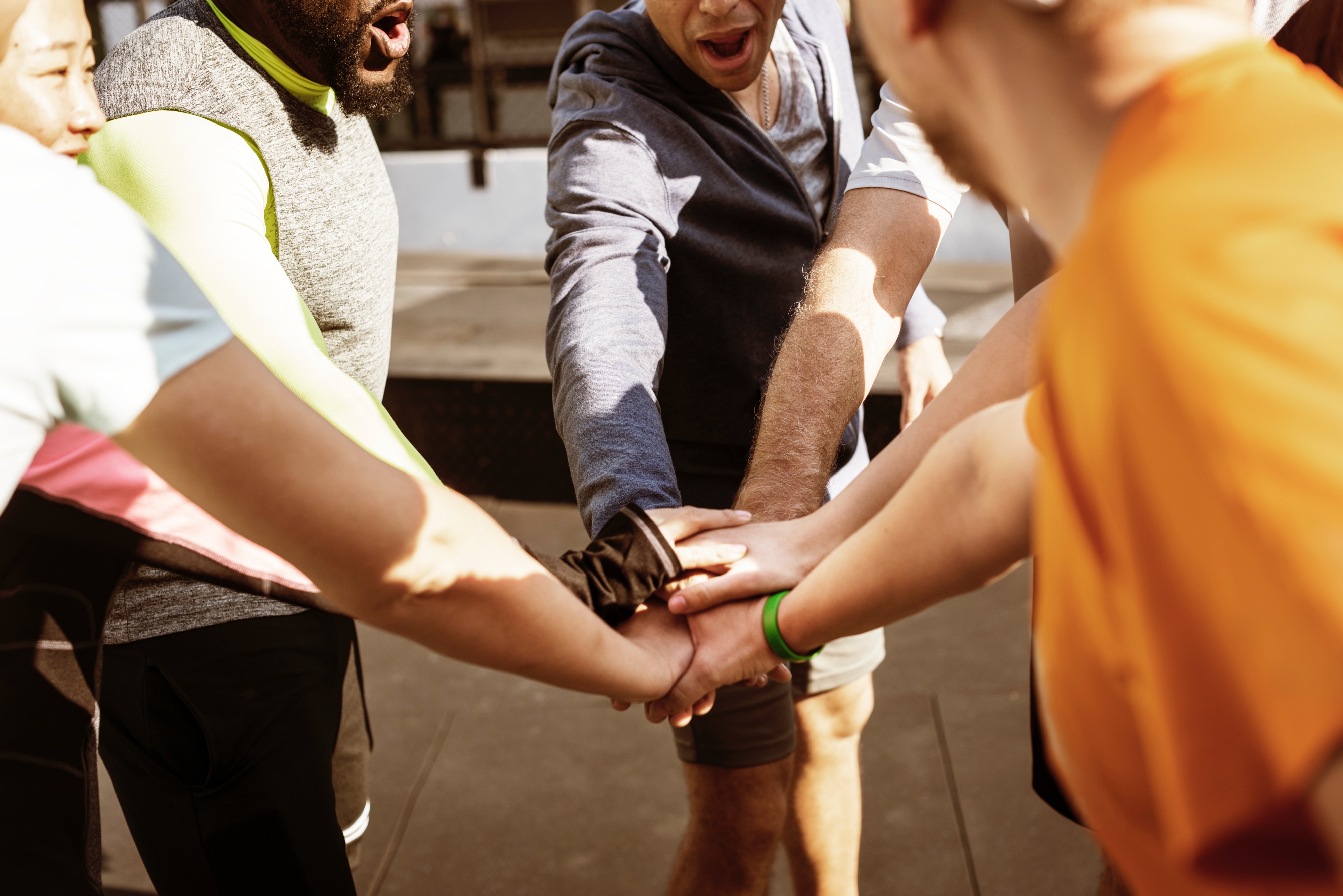 A group of people stood in a circle with their hands all meeting in the middle